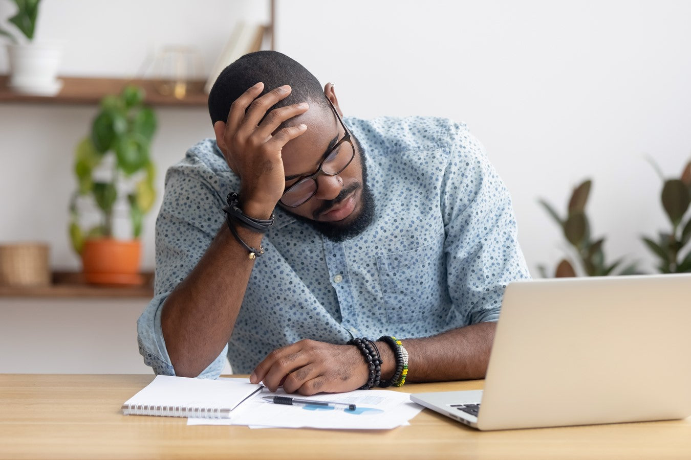 man with head in hand in front of laptop