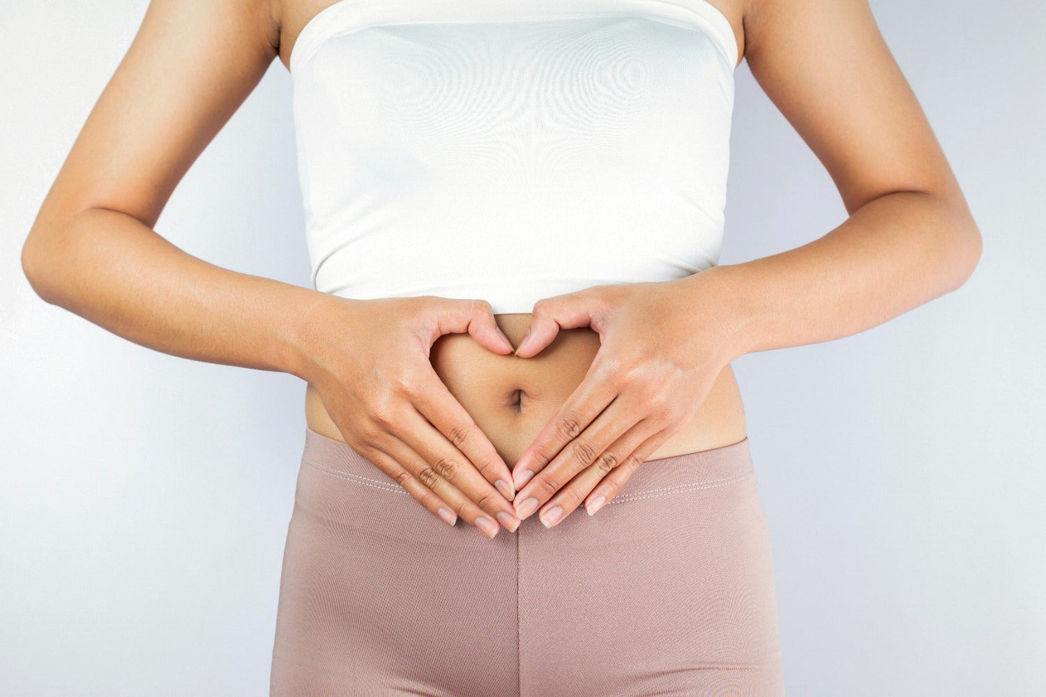 woman making a heart shape in front of stomach