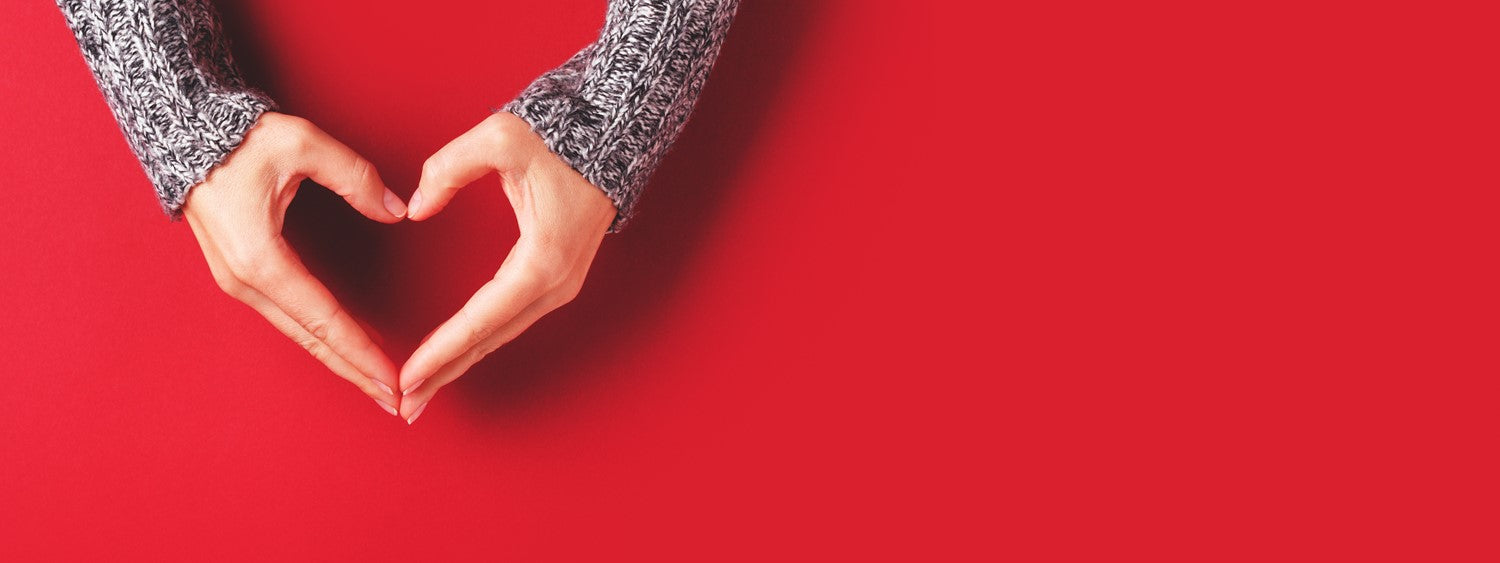 hands forming a heart in front of red background