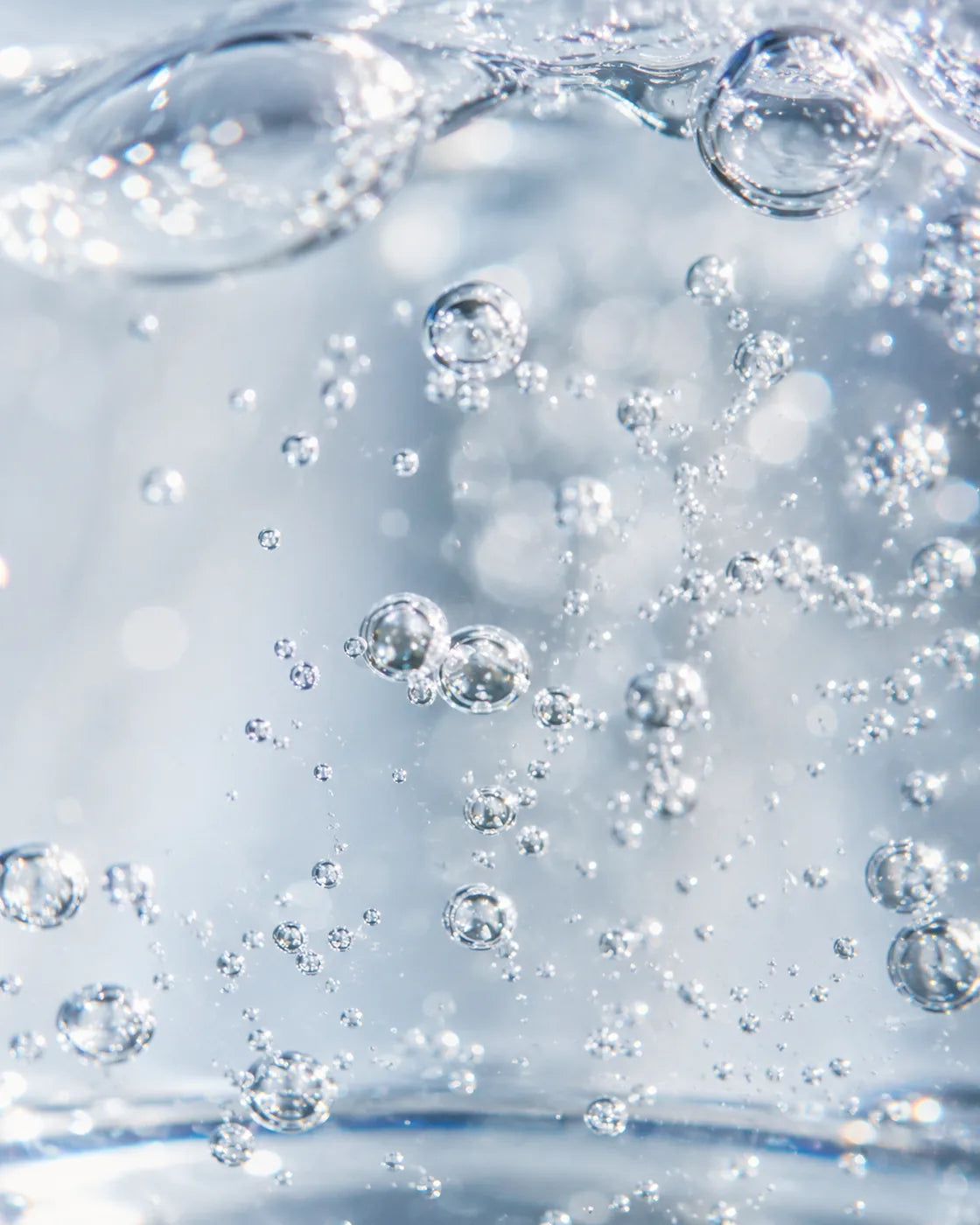 Extreme close-up of fresh, crystal-clear water with fine bubbles and light